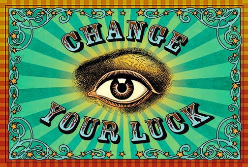A card that reads "change your luck" in vintage circus style lettering, a vintage illustration of an eye with golden and turquoise rays and a striped border in orange and yellow with swirls and stars
